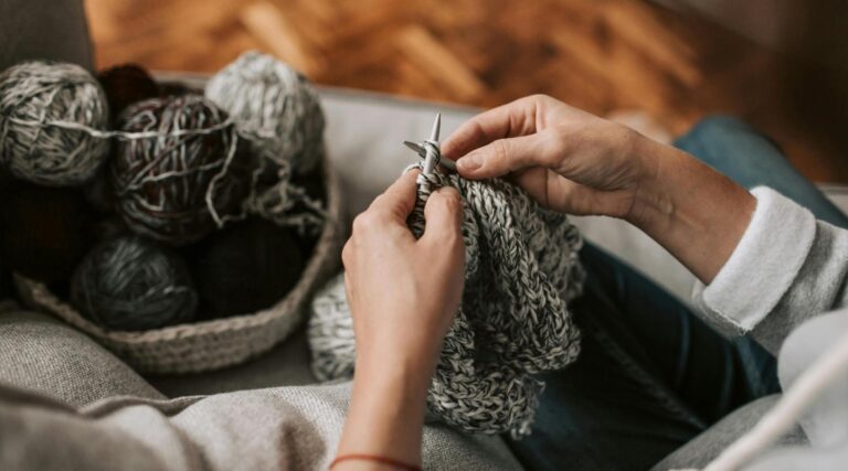 A close up picture of someone knitting with chunky yarn in a cosy winter knitting scene