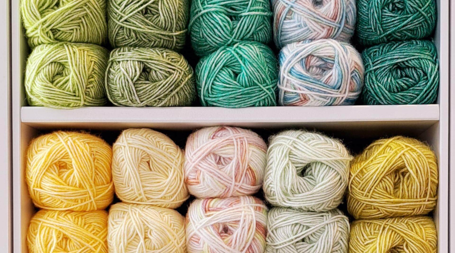 A close up picture of balls of Stone Washed by Scheepjes - a vegan yarn option at Baa - stacked in a cube. The colours are a mix of bright yellows and greens.